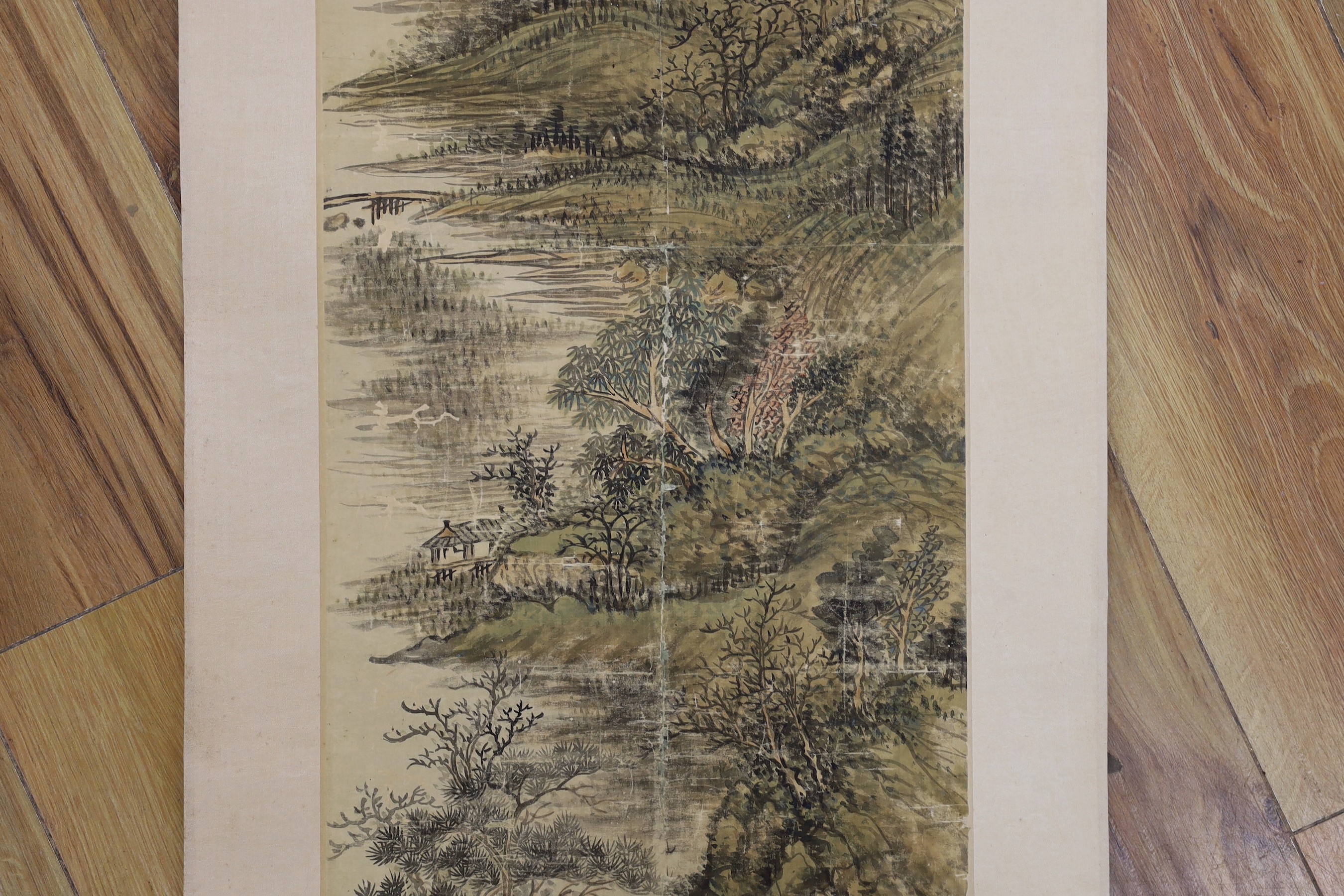 A Chinese landscape scroll painting on silk, Qing dynasty inscribed and signed, artist’s seal and collector’s seal lower left, image 139cm x 27.5cm, remounted
